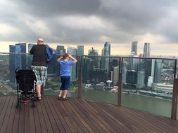 man and boy looking at city from marina bay sands hotel, singapore