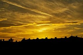 golden sunset sky above dark houses silhouettes, england