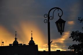 vintage street lantern and buildings silhouettes at sunset sky, poland, gniezno