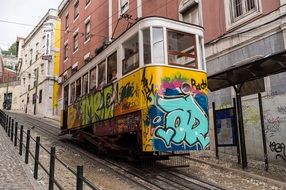 tram with graffiti on old cobblestone street, portugal, lisbon