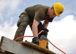 a builder in a yellow helmet on building roof