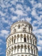 top of leaning tower at white clouds in blue sky, italy, pisa