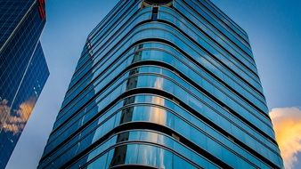 city skyscraper with reflection of golden sunset clouds on glass facade