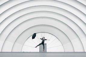 jumping girl with umbrella at arched construction