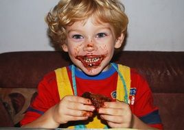 happy child boy eating chocolate muffin