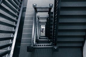 person lying on floor under tall staircase