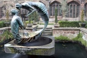 sculpture of woman and man with bowl on pond at ancient castle