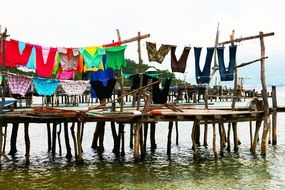 bright clothes drying on line above wooden pier