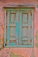 weathered green shutters on window in old pink facade, greece, samos