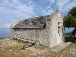 small grey stone church at sea, croatia, veli losinj