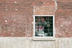 grated window with potted flowers on red brick wall