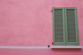 pink wall with green closed shutters on window