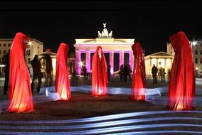 ladies in red garments at brandenburg gate, light show, germany, berlin