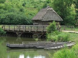 19th century village house and boats on water at bridge, open air museum, poland