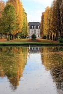 luxury mansion in beautiful autumn park with mirroring on water