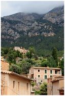 old village buildings at foggy mountains, spain, mallorca, deia