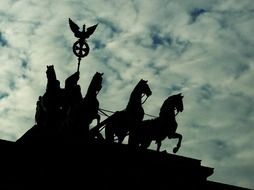 silhouette of quadriga atop brandenburg gate at clouds, germany, berlin