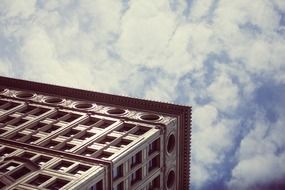 corner of rectangular building at blue sky background with white clouds