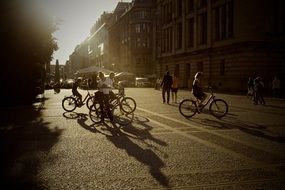 people with bicycles on street in town at summer sunset