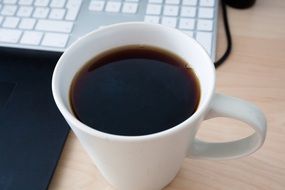 coffee cup at keyboard on desk