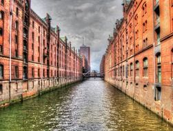 old red brick buildings at channel under grey clouds, germany, hamburg, speicherstadt