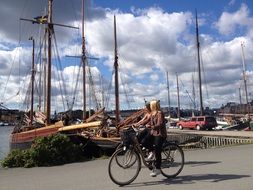 two young girls riding bicycles at harbour at blue sky background with white clouds, sweden, stockholm