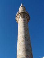 grey minaret tower at blue sky background