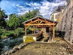 shed at water beside old stone wall, france