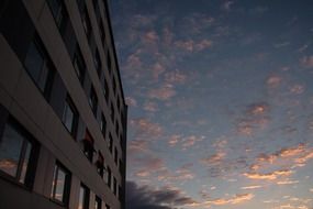 pink sunrise clouds at dark blue sky mirroring on windows