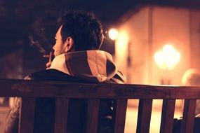 man smoking cigarette on the bench