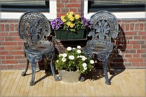 antique chairs and potted flowers outside house