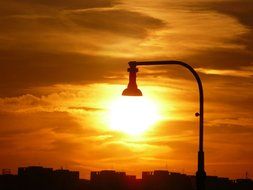 sun at street lamp above city at sunset