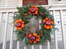 decorative christmas wreath with fruits on wooden fence