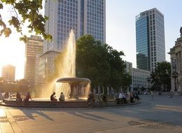 people at fountain at summer evening in city, germany, frankfurt