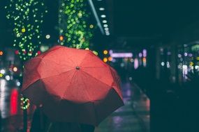 man under a red umbrella on a city street