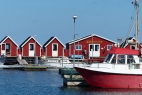 red fishermen’s cabins and boat at pier in scandinavia