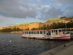 tourist boat at pier in view of city at evening, germany, hamburg