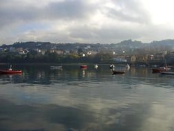 boats on calm water at coastal village under clouds