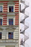 man on emergence spiral staircase at facade, germany, berlin