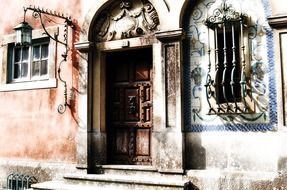 old ornate facade with wrought iron grates on window and lantern, portugal