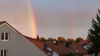 double rainbow above red tile roofs