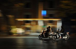 people riding scooters on night street
