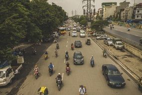 people riding scooters among cars on road in city, vietnam, hanoi