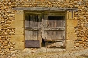 fragment of old barn, stone wall with wooden gate, france, dordogne