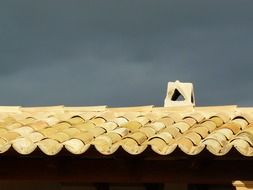 old yellow tile roof under grey clouds