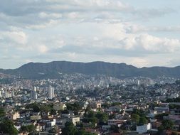 top view of modern city at mountains under white clouds, brazil