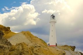 walk path on rock to Castlepoint Lighthouse at clouds, new zealand