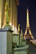 Gilded bronze statues in the central square of the Palais de Chaillot and eiffel tower with colorful lights at night, france, paris