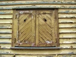 window with closed shutters on weathered wooden facade