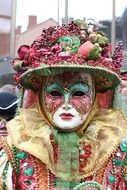 portrait of masked person in hat, decorated with fruits and berries on carnival, italy, venice